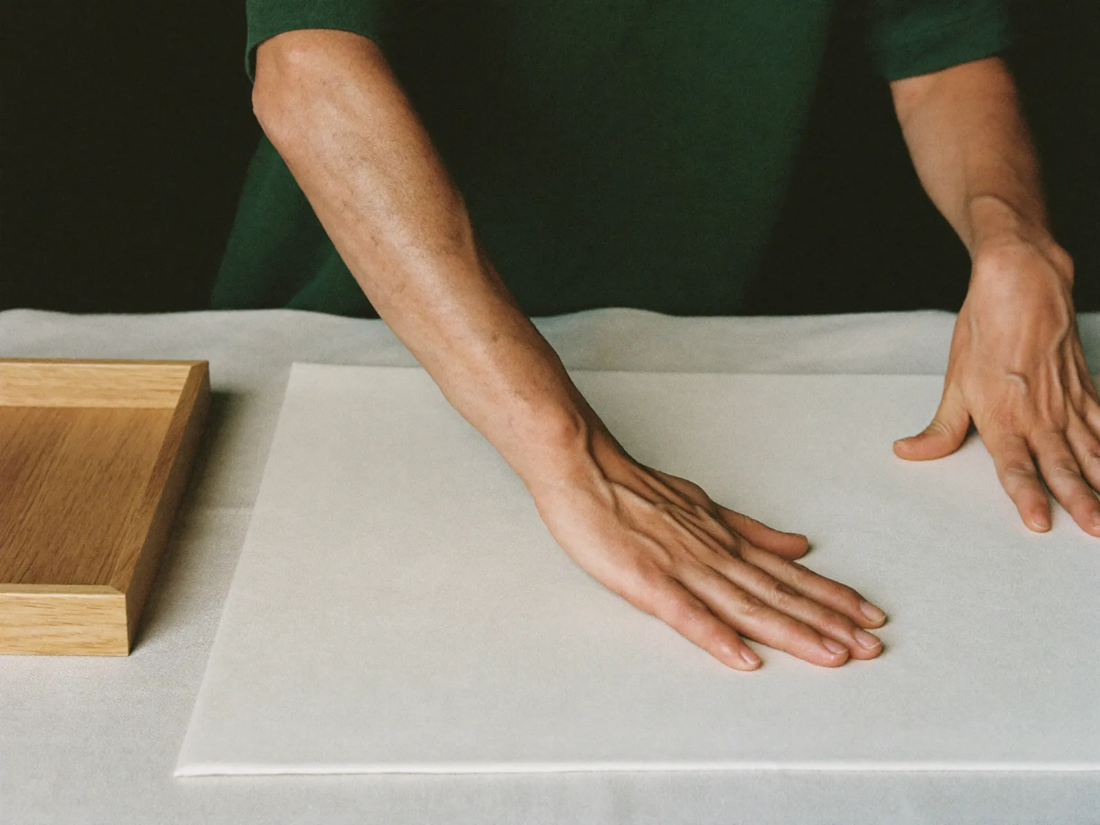 Hands smoothing out one extra-large body cloth on a table.